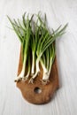 Fresh green onions on a rustic wooden board over white wooden background, side view Royalty Free Stock Photo