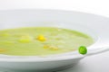 Fresh green pea on the edge of a white plate with vegetable soup Royalty Free Stock Photo