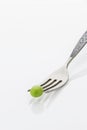 Fresh green pea on fork closeup, on white