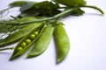 Fresh green pea pods with foliage on a white background. One pod is open, peas are visible.