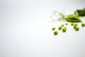 Fresh green pea pods with foliage on a white background. One pod is open, peas are visible.