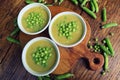 Fresh green pea soup with pea seeds and pea pods around . Selective Focus, Focus on the pea in the middle of the soup Royalty Free Stock Photo