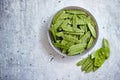 Fresh green peas in white ceramic bowl on gray stone background Royalty Free Stock Photo