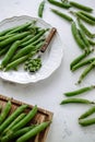 Fresh green peas on a white plate with a wooden spoon, close-up Royalty Free Stock Photo