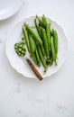 Fresh green peas on a white plate with a wooden spoon, flat lay Royalty Free Stock Photo
