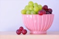 Red and green grapes in pink bowl