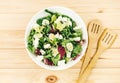 Fresh green salad with goat cheese, eggs in big white bowl on wooden table. Vegan salad with green mix leaves and vegetables Royalty Free Stock Photo