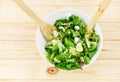 Fresh green salad with goat cheese, eggs in big white bowl on wooden table. Vegan salad with green mix leaves and vegetables Royalty Free Stock Photo