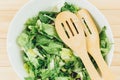 Fresh green salad with goat cheese, eggs in big white bowl on wooden table. Vegan salad with green mix leaves and vegetables Royalty Free Stock Photo