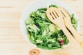 Fresh green salad with goat cheese, eggs in big white bowl on wooden table. Vegan salad with green mix leaves and vegetables Royalty Free Stock Photo