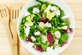 Fresh green salad with goat cheese, eggs in big white bowl on wooden table. Vegan salad with green mix leaves and vegetables Royalty Free Stock Photo