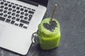 Fresh green smoothie with banana and spinach with heart of sesame seeds and a laptop Love for a healthy raw food concept Royalty Free Stock Photo