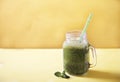 Fresh green smoothie in a mug jar and a mint leaf on a yellow background. Copy spaes