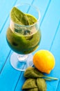 Fresh green smoothie with spinach leaf and lemon in glass on blue background, spinach, cucumber, apple fruit drink, prod Royalty Free Stock Photo