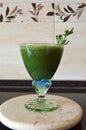 Fresh green smoothie in a wide glass on stem on the kitchen countertop - close up front top view Royalty Free Stock Photo