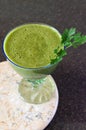 Fresh green smoothie in a wide glass on stem on the kitchen countertop - close up front top view Royalty Free Stock Photo