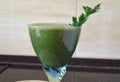 Fresh green smoothie in a wide glass on stem on the kitchen countertop - close up front top view Royalty Free Stock Photo