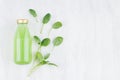 Fresh green spinach juice in glass bottle with green leaves on white wood board, top view, copy space, mock up for design. Royalty Free Stock Photo