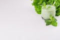 Fresh green spinach smoothie drink with straw, twig mint, salad on soft white wood table, closeup. Royalty Free Stock Photo