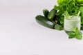 Fresh green spinach smoothie drink with straw, twig mint, salad, vegetables on soft white wood table. Royalty Free Stock Photo