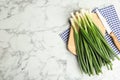 Fresh green spring onions, knife and cutting board on marble table, flat lay. Space for text Royalty Free Stock Photo