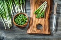 Fresh green spring scallions wooden cutting board kitchen knife vintage wood background Royalty Free Stock Photo