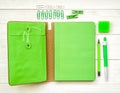 Fresh green stationary. green notebook with eraser, pen,pencil and paper clips on white wooden background Royalty Free Stock Photo