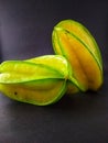 Fresh and green sweet starfruit agains black background