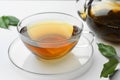 Fresh green tea in glass cup with saucer and leaves on white table, closeup Royalty Free Stock Photo