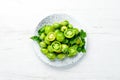 Fresh green tomatoes in a plate on a white wooden background. Greens. Top view. Royalty Free Stock Photo