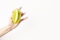 Fresh green tropical carambola in woman hand with red nails, isolated on white background. Hipster style vegetables fruits for lay