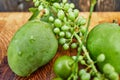 Fresh green unripe grapes, tangerines and mangoes on a wooden background Royalty Free Stock Photo