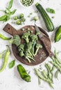 Fresh green vegetables - broccoli, zucchini, green peas and beans, peppers on wooden cutting board on a light background. Royalty Free Stock Photo