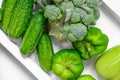 Fresh green vegetables - courgette, cucumber, paprika, parsley, broccoli on white tray and white background. Healthy snacks, Royalty Free Stock Photo