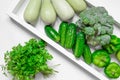 Fresh green vegetables - courgette, cucumber, paprika, parsley, broccoli on white tray and white background. Healthy snacks,
