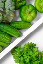 Fresh green vegetables - courgette, cucumber, paprika, parsley, broccoli on white tray and white background. Healthy snacks,