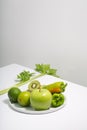 Fresh green vegetables and fruits on white table