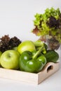 Fresh green vegetables and fruits in wooden boxes on white background. Bell pepper, apples, zucchini, celery, salad leaves. Royalty Free Stock Photo