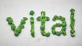 Fresh green veggies spell vital on grey surface Royalty Free Stock Photo