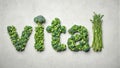 Fresh green veggies spell vital on grey surface Royalty Free Stock Photo