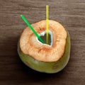 Fresh green young coconut with cut out heart shape and straws on wooden background