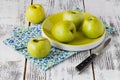 Fresh greenish apples in a dish on a rustic background.