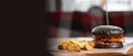 Fresh grilled black beef burger and french fries on a wooden table in fast food restaurant Royalty Free Stock Photo