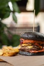 Fresh grilled black beef burger and french fries on a wooden table in fast food restaurant Royalty Free Stock Photo