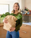 Fresh from the grocers. Portrait of a smiling young woman standing in her kitchen carrying a paper bag full of groceries Royalty Free Stock Photo