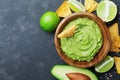 Fresh guacamole dip with avocado, lime and nachos on black table top view. Copy space.Traditional mexican food. Royalty Free Stock Photo