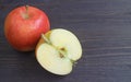 Fresh half cut red apple with a whole fruit on black wooden table Royalty Free Stock Photo