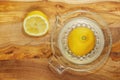 Fresh half lemon on glass juicer on a wooden board. Juice is on the bottom of jar. Close up. Top down view Royalty Free Stock Photo