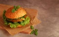 fresh hamburger with cutlet, cucumber, tomato and salad on a wooden board and grey background