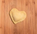 Fresh,handmade single raviolo in the shape of heart,covered with flour and placed on the wooden table. Royalty Free Stock Photo